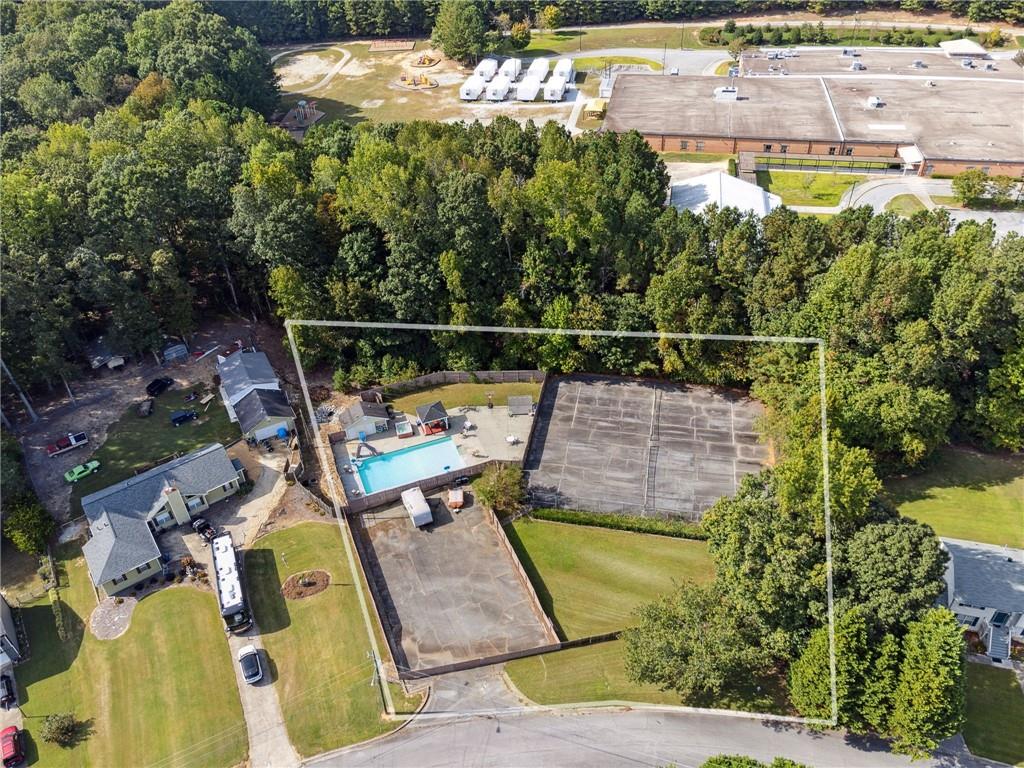 an aerial view of a swimming pool with a yard and seating area