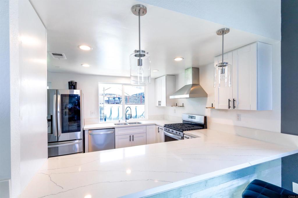 a large kitchen with kitchen island a large counter top space a sink stainless steel appliances and cabinets