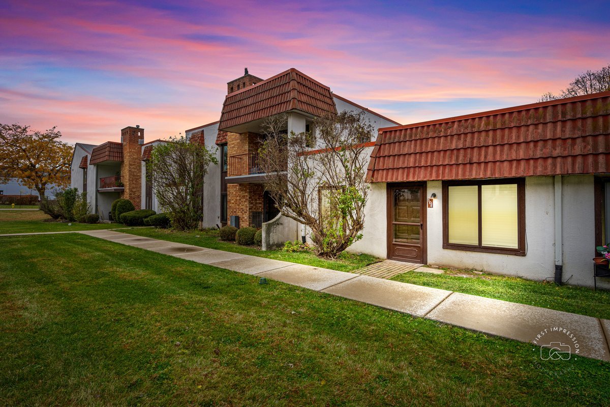 a view of a house with a small yard and a large parking space