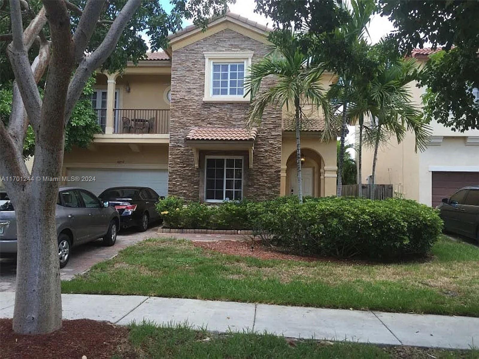 a front view of a house with a garden and trees