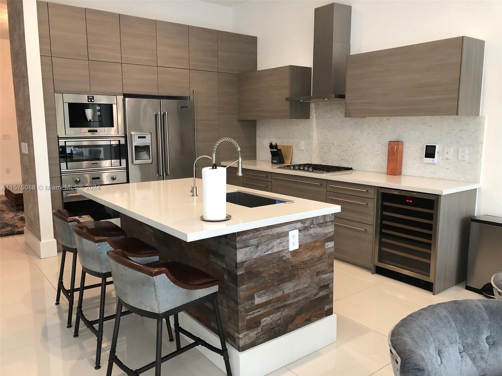 a kitchen with stainless steel appliances kitchen island a table chairs in it and wooden floors