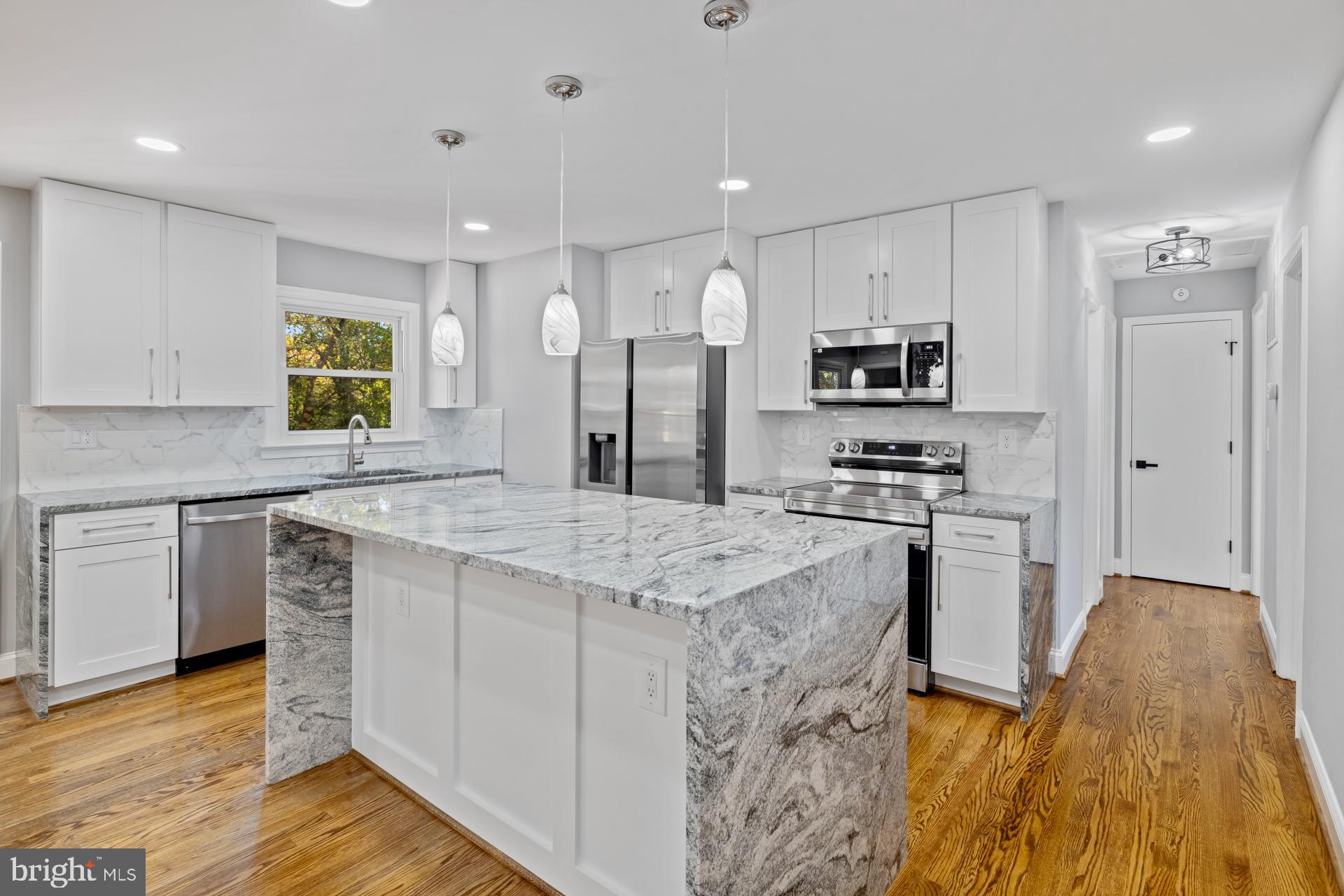 a kitchen with stainless steel appliances kitchen island granite countertop a stove a sink and a refrigerator