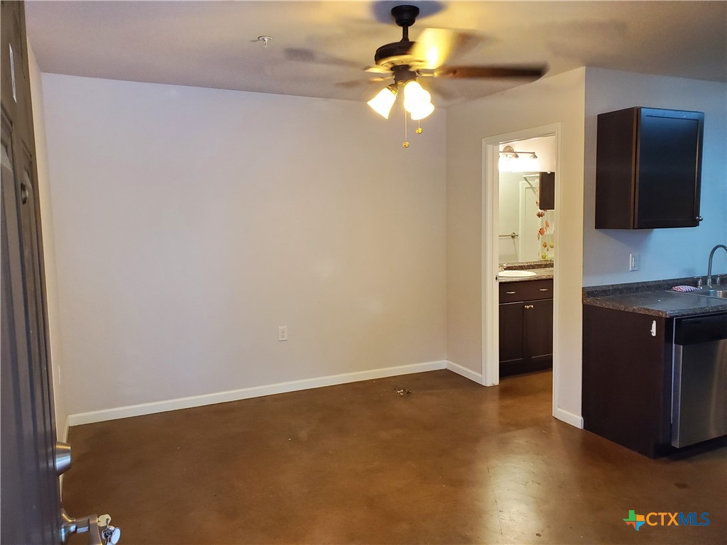 an empty room with a flat screen tv and kitchen view