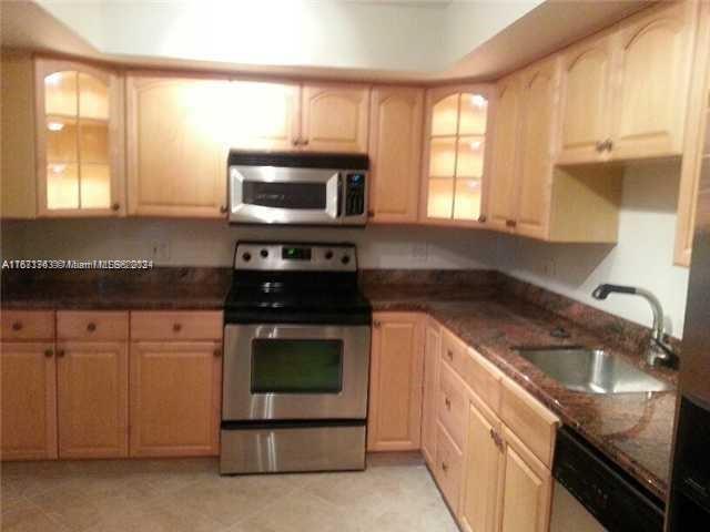 a kitchen with granite countertop a stove sink and microwave