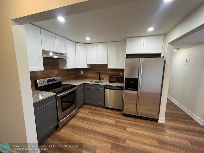 a kitchen with granite countertop a refrigerator and a stove top oven