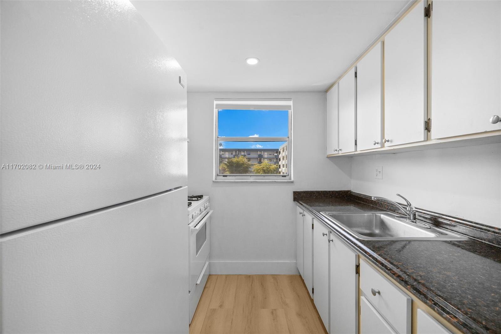 a kitchen with granite countertop a sink a stove a refrigerator and cabinets