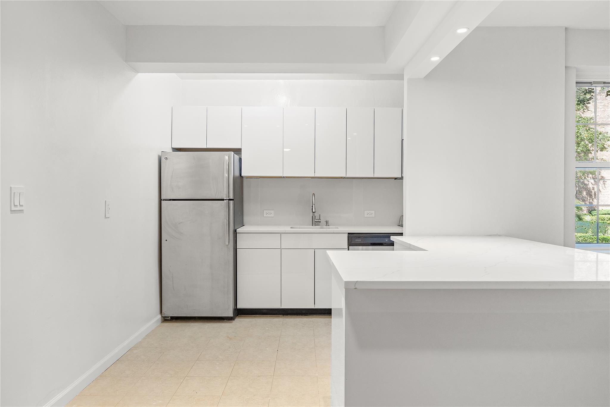 a kitchen with a refrigerator sink stove and white cabinets