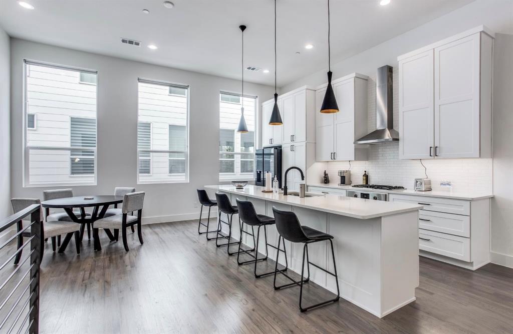 a kitchen with sink stove and white cabinets with wooden floor