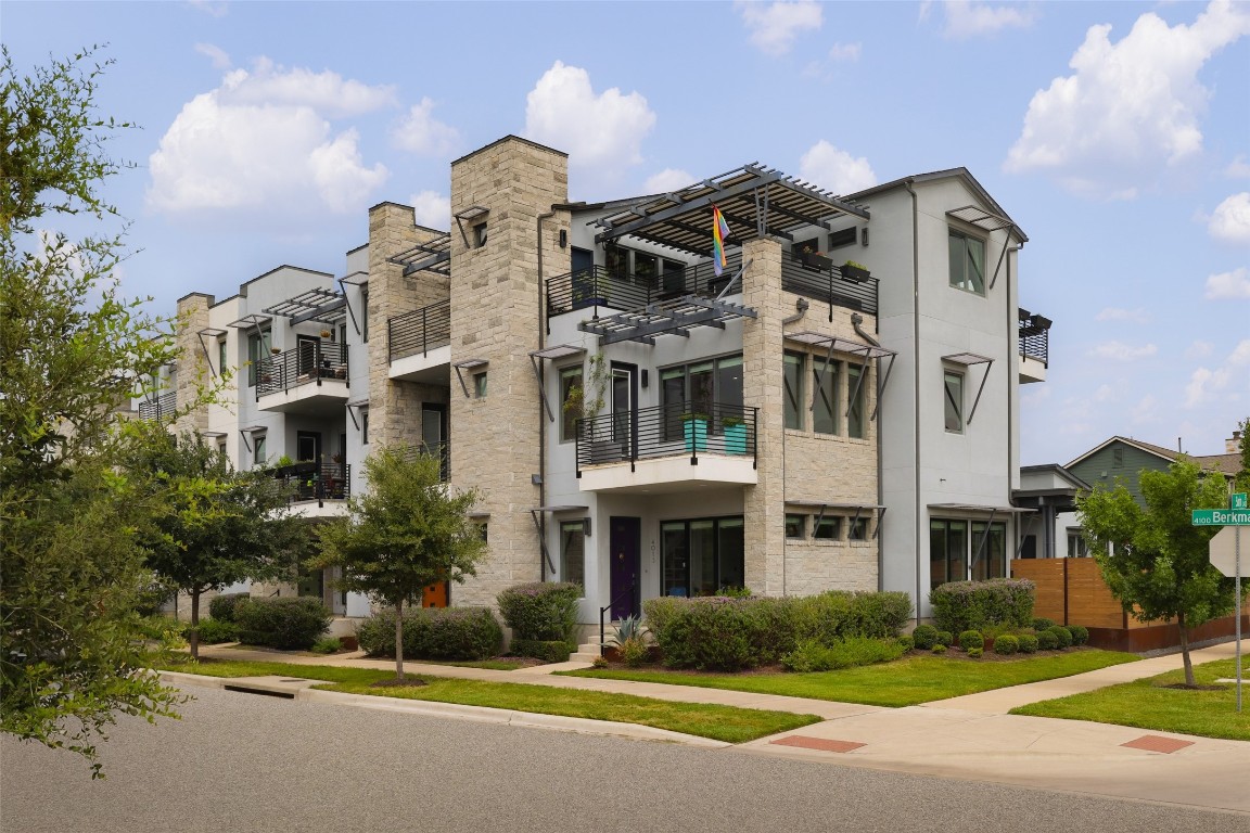 a front view of a multi story residential apartment building with yard and traffic signal