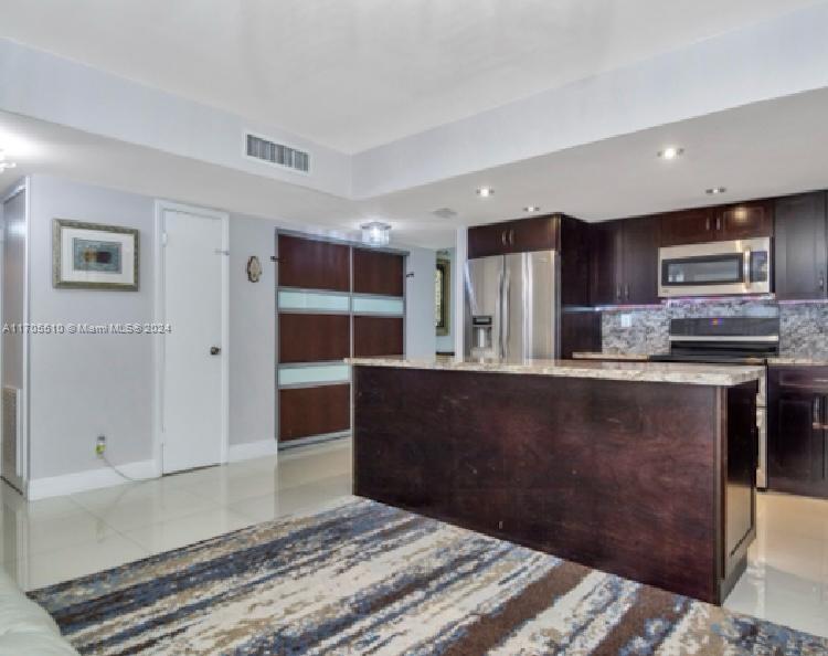 a kitchen with granite countertop a refrigerator and cabinets