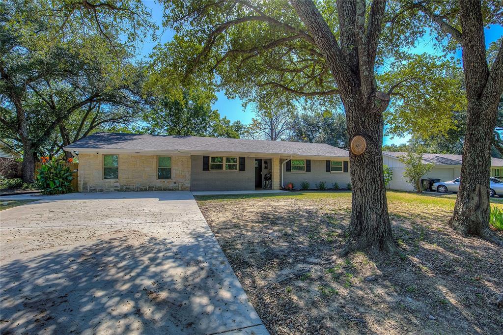 a view of a house with a yard and large tree