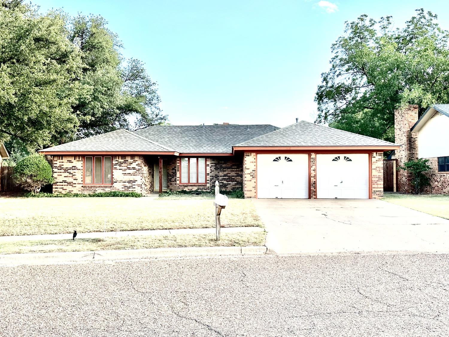 a front view of a house with a road and trees