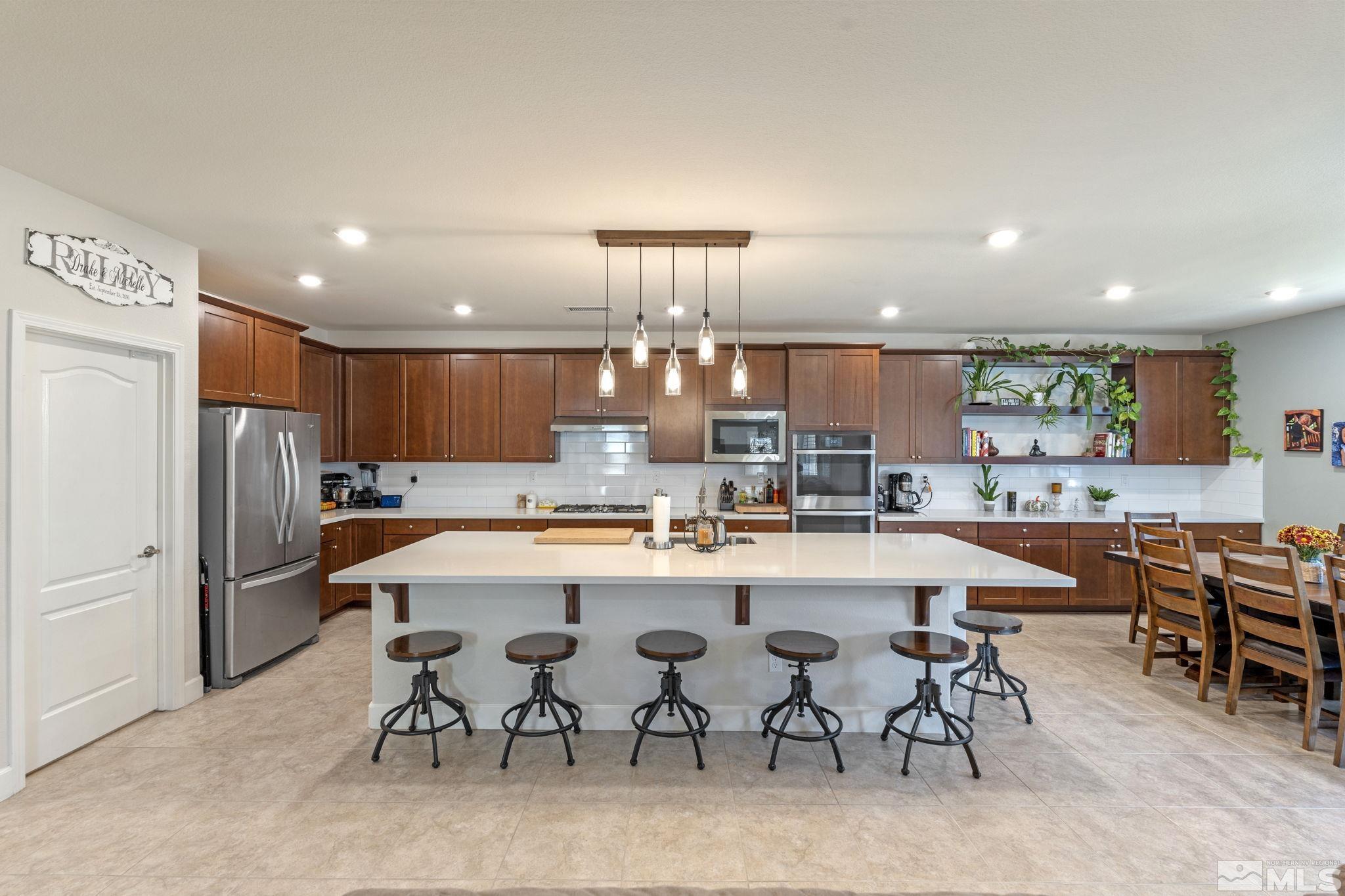 a kitchen with stainless steel appliances a dining table chairs and stove top oven