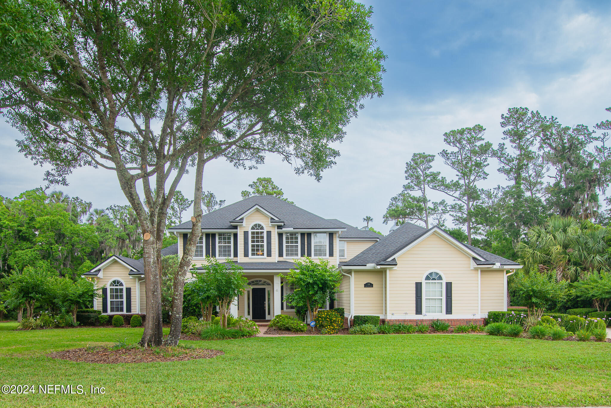 a front view of a house with a garden and trees