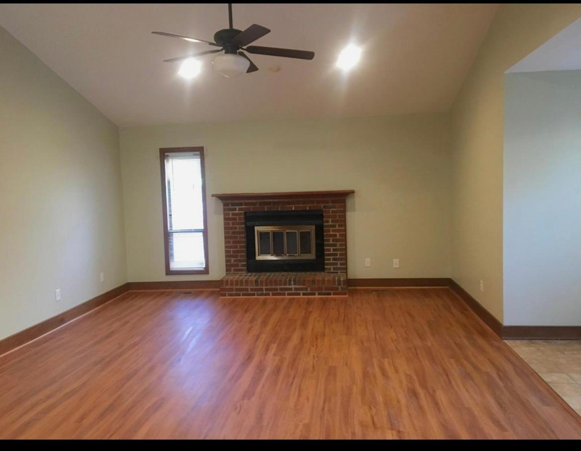 a view of an empty room with a fireplace and a window