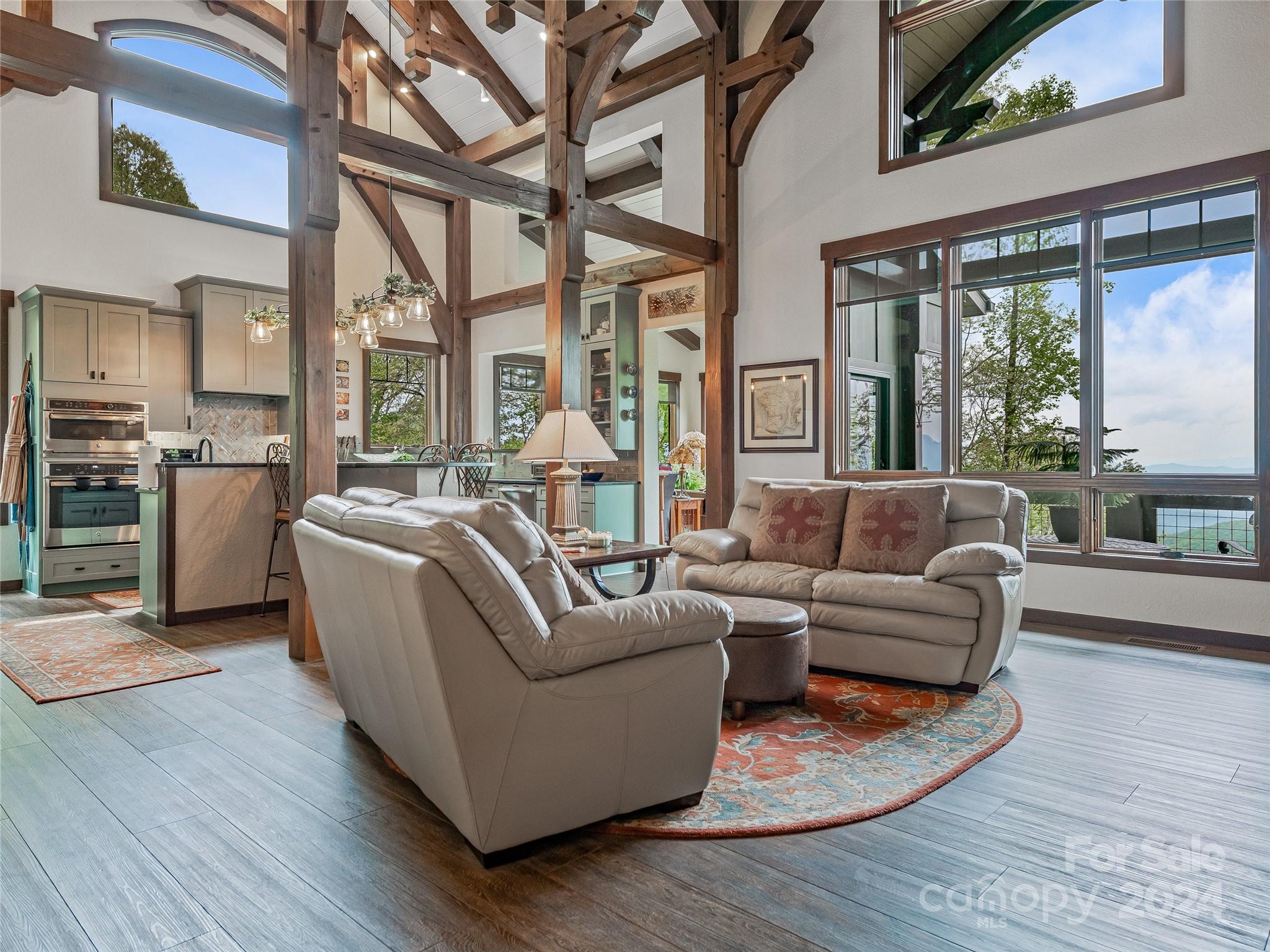 a living room with furniture large windows and wooden floor