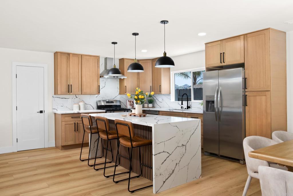 a kitchen with stainless steel appliances granite countertop a table chairs refrigerator and sink