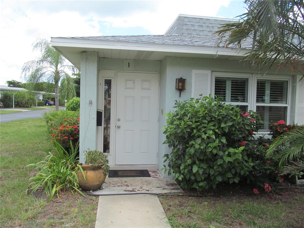 a view of a house with potted plants and a bench