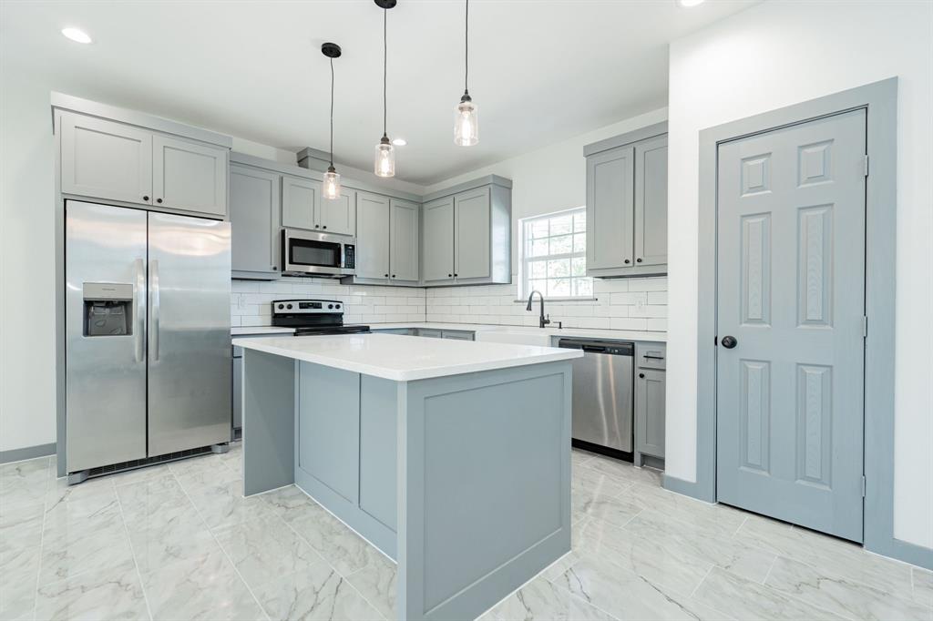 a kitchen with kitchen island a sink stainless steel appliances and cabinets