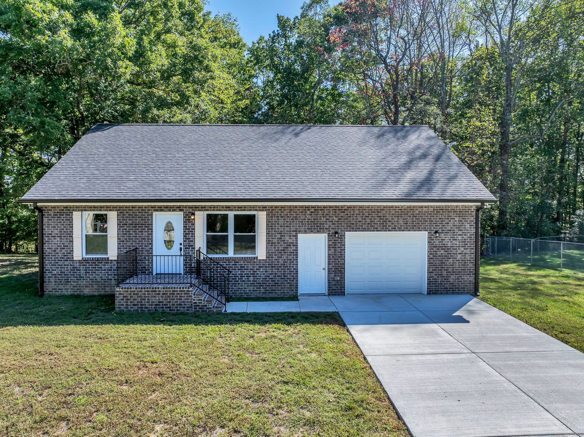 a front view of house with yard and trees in the background