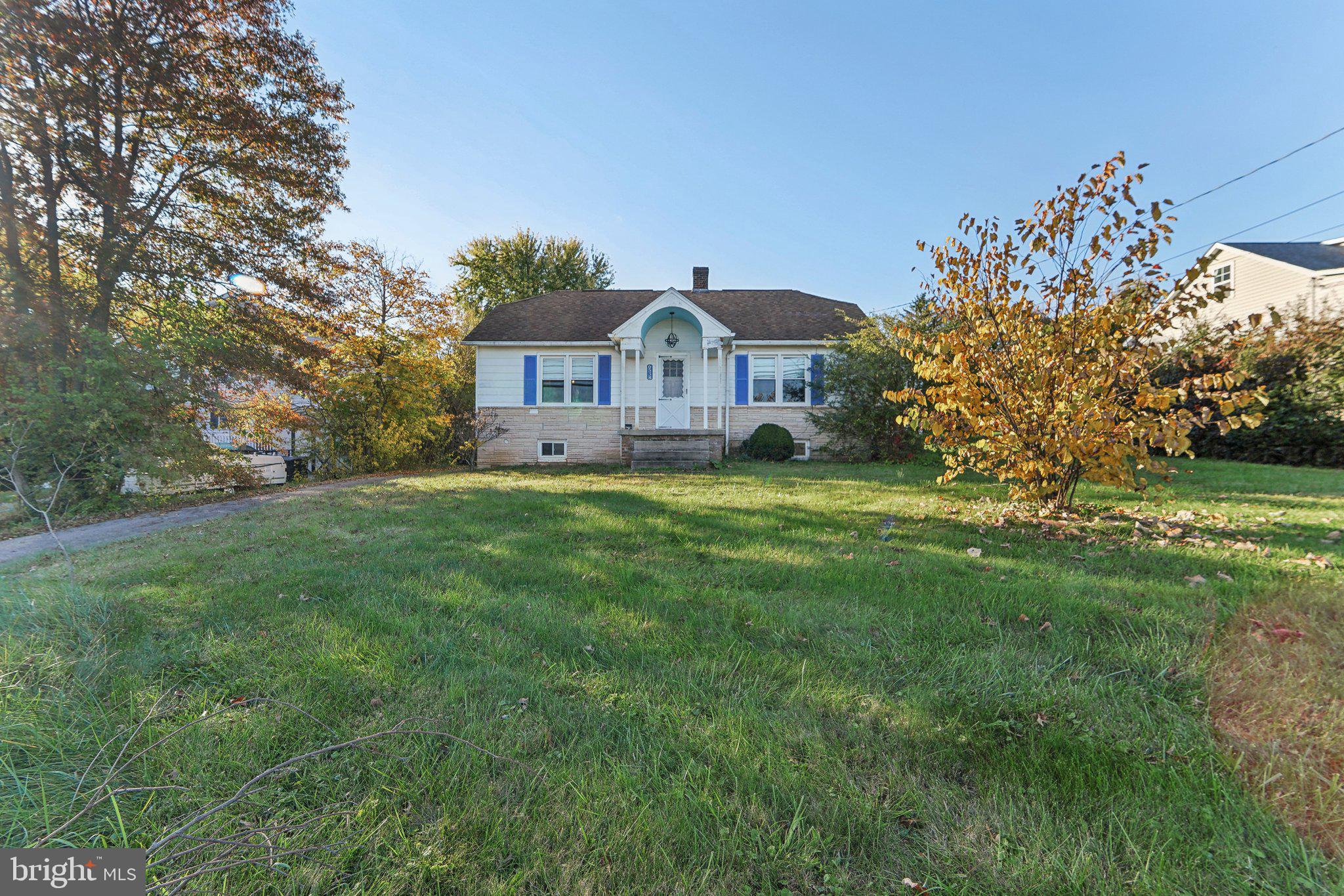 a front view of a house with a yard and large tree