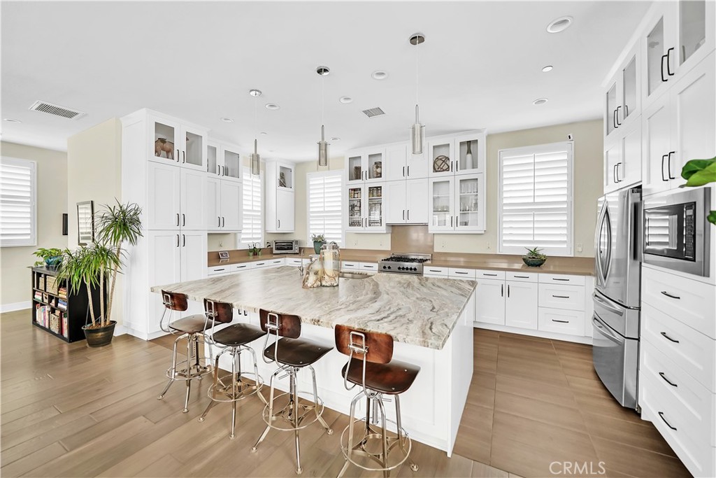 a large white kitchen with granite countertop a stove a sink a dining table and chairs