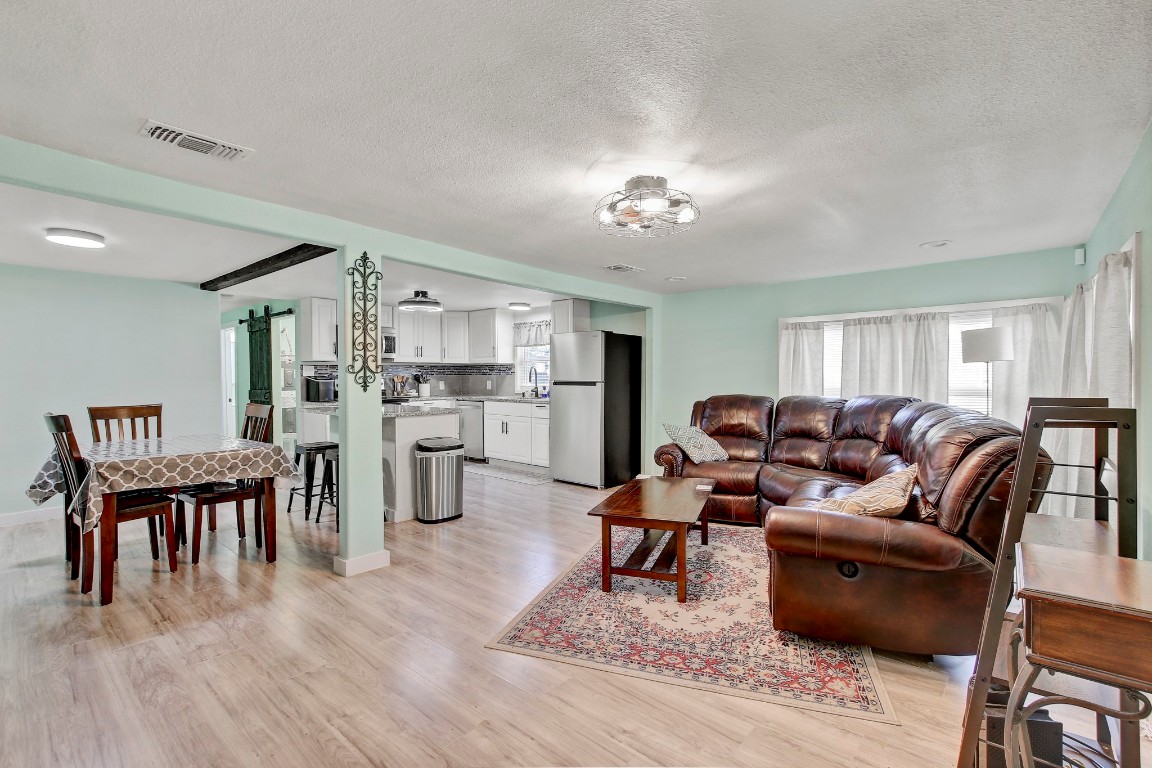 a living room with furniture wooden floor and kitchen view