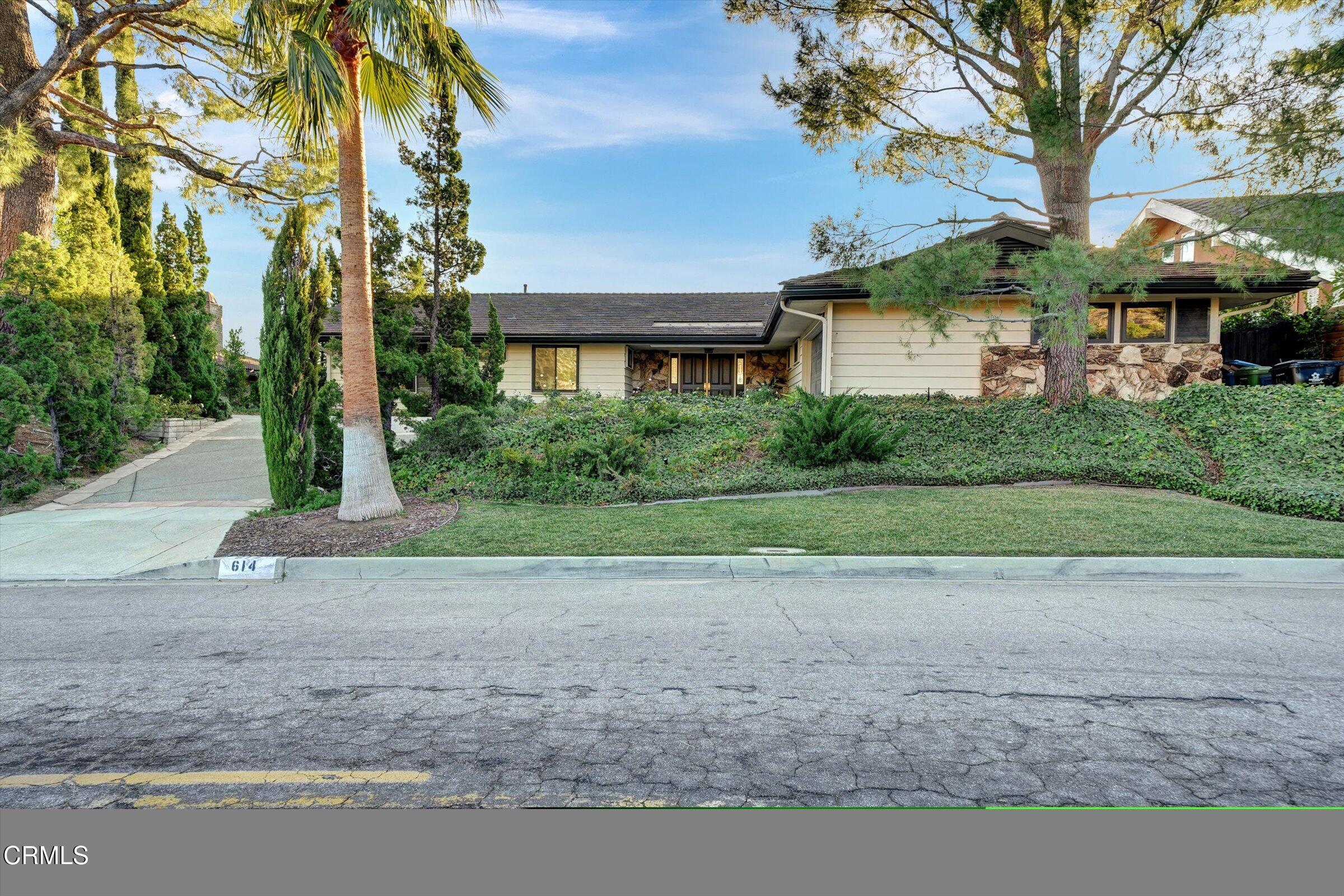 a front view of a house with a yard and trees