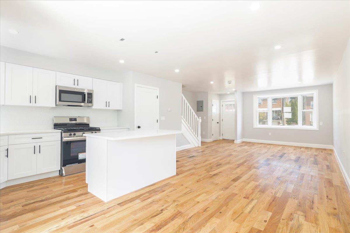 Kitchen featuring appliances with stainless steel finishes, a center island, light hardwood / wood-style floors, and white cabinetry