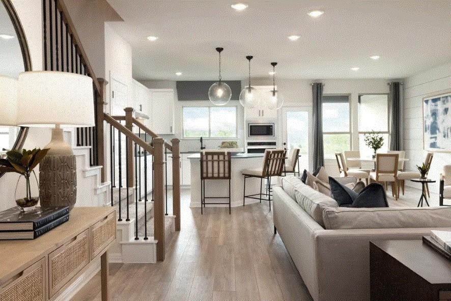 a living room with furniture kitchen view and a wooden floor