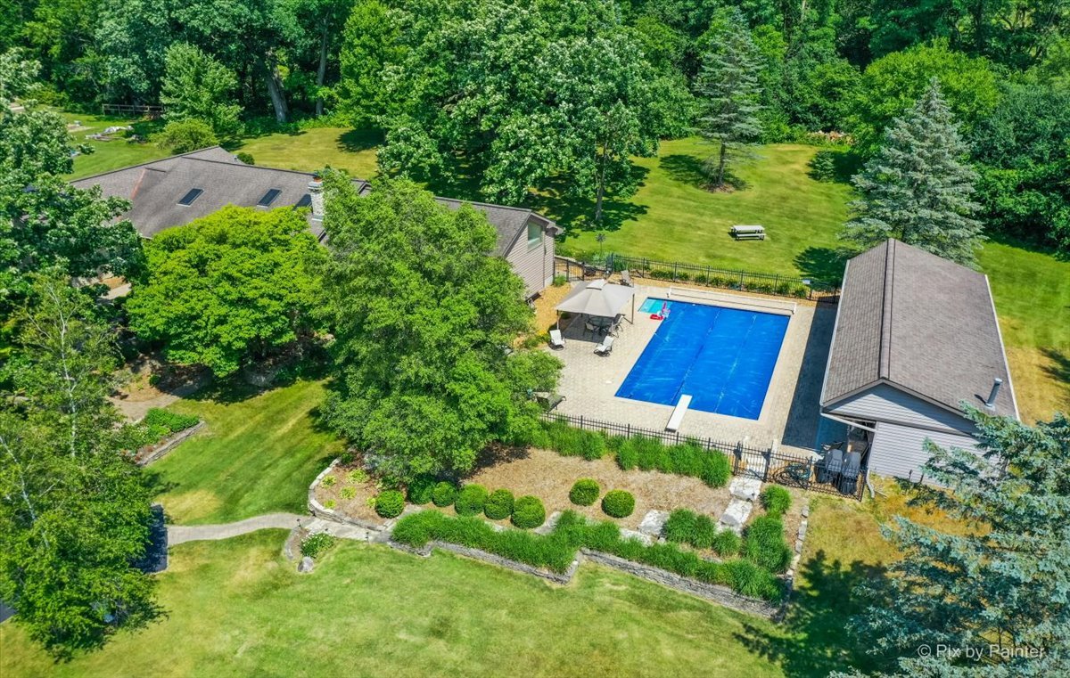 an aerial view of residential house with outdoor space and trees all around