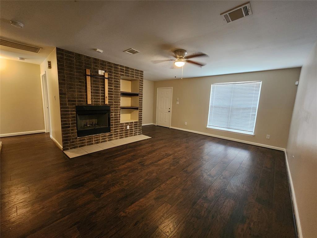 an empty room with wooden floor fireplace and windows