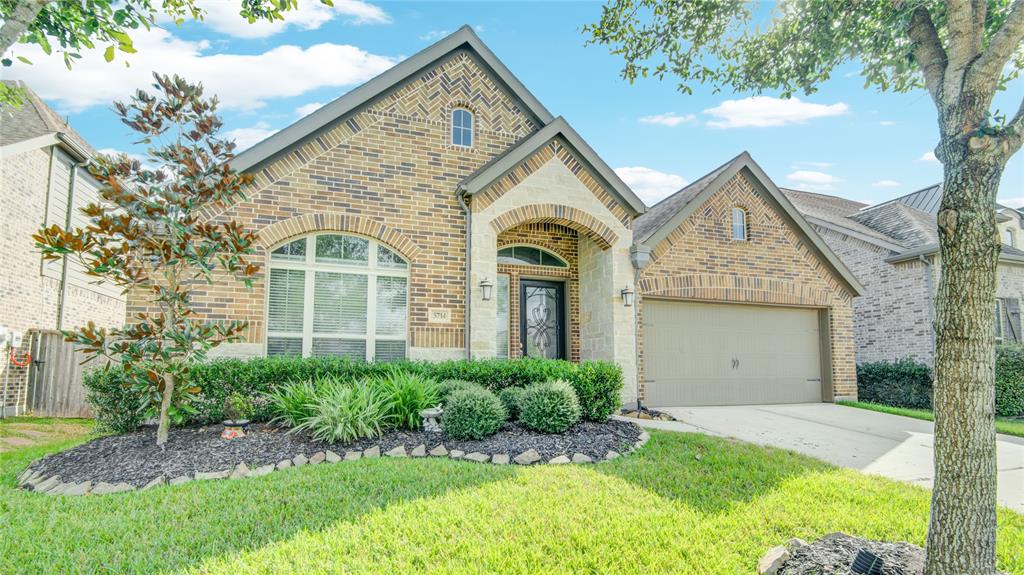 A charming one-story brick house with stone accents features a striking tall glass front door, blending traditional and modern elements seamlessly.