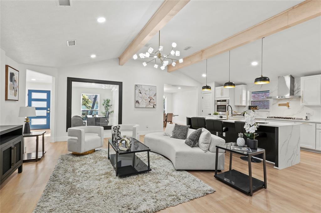 Living room with a chandelier, light hardwood / wood-style flooring, and lofted ceiling with beams