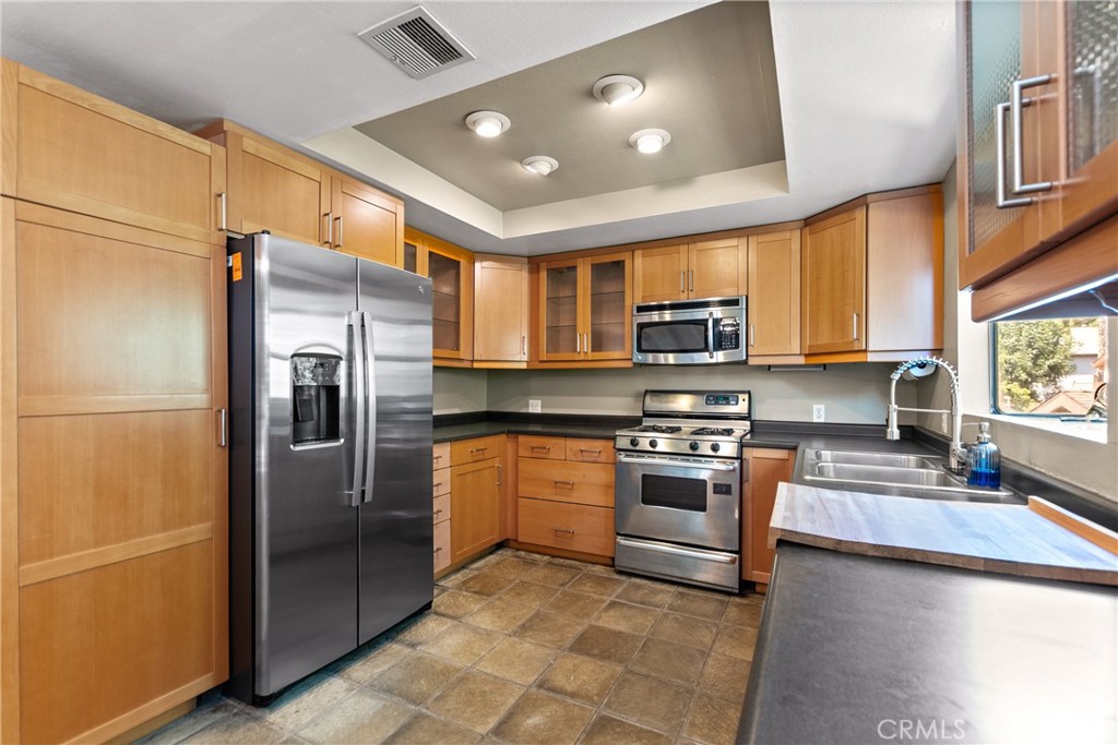 a kitchen with stainless steel appliances granite countertop a refrigerator a stove top oven a sink and dishwasher