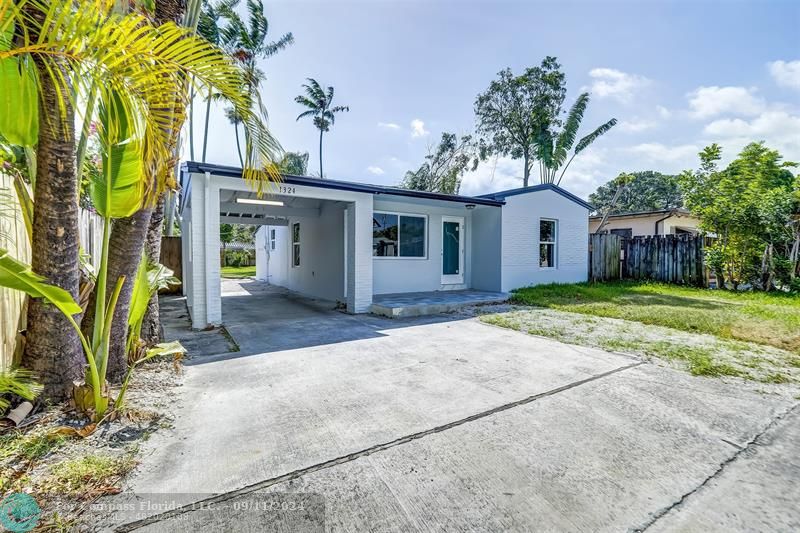 a view of a house with a yard and palm trees