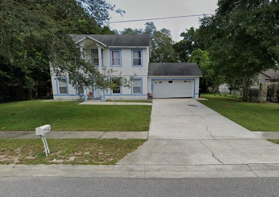 a view of a house with a yard and large tree