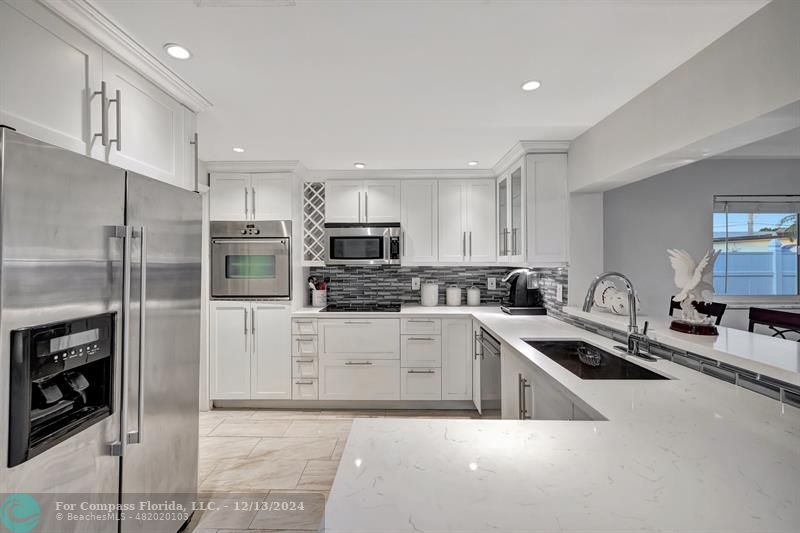 a kitchen with stainless steel appliances a sink a stove a refrigerator cabinets and a counter top space