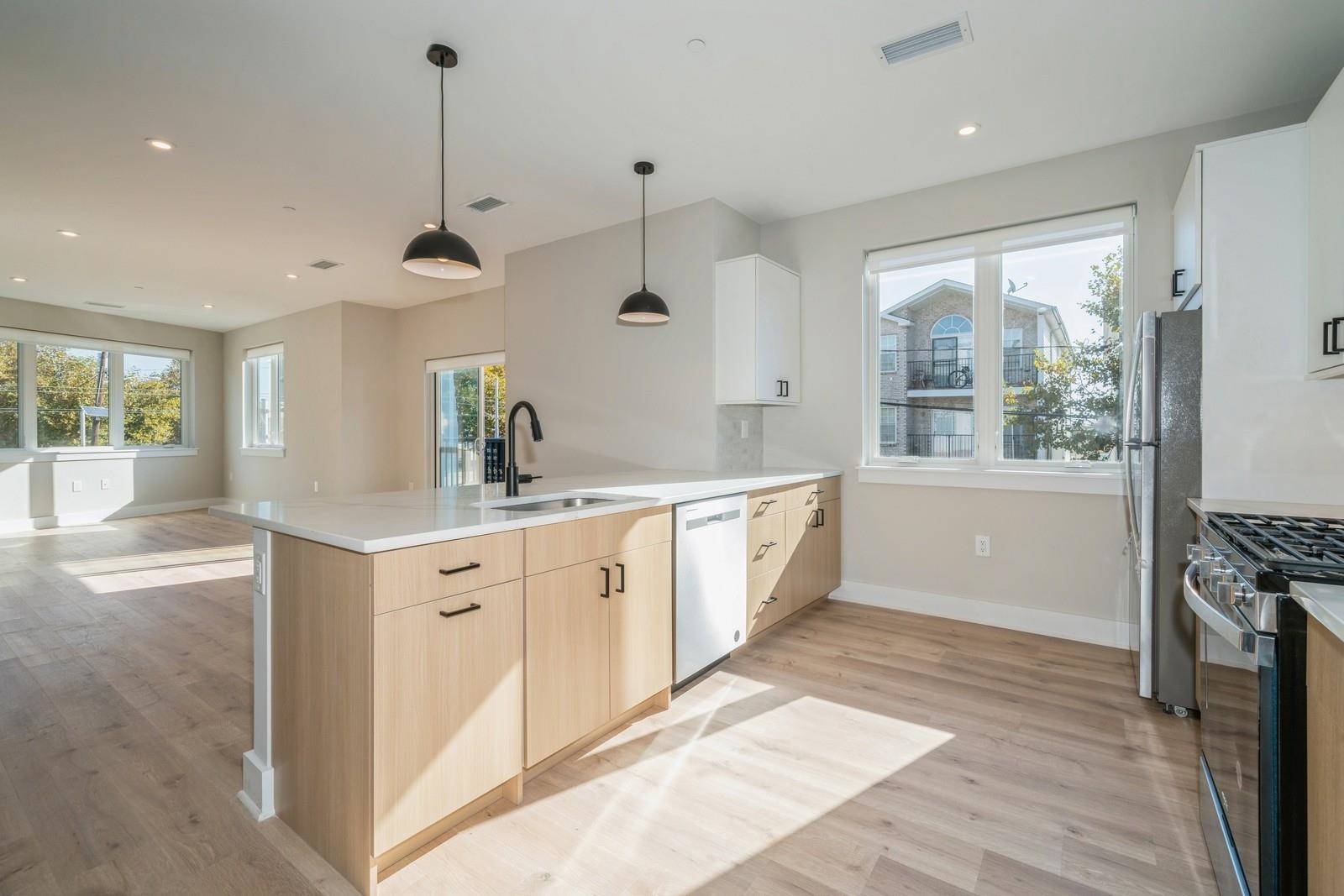 a large white kitchen with a large window a sink and stainless steel appliances