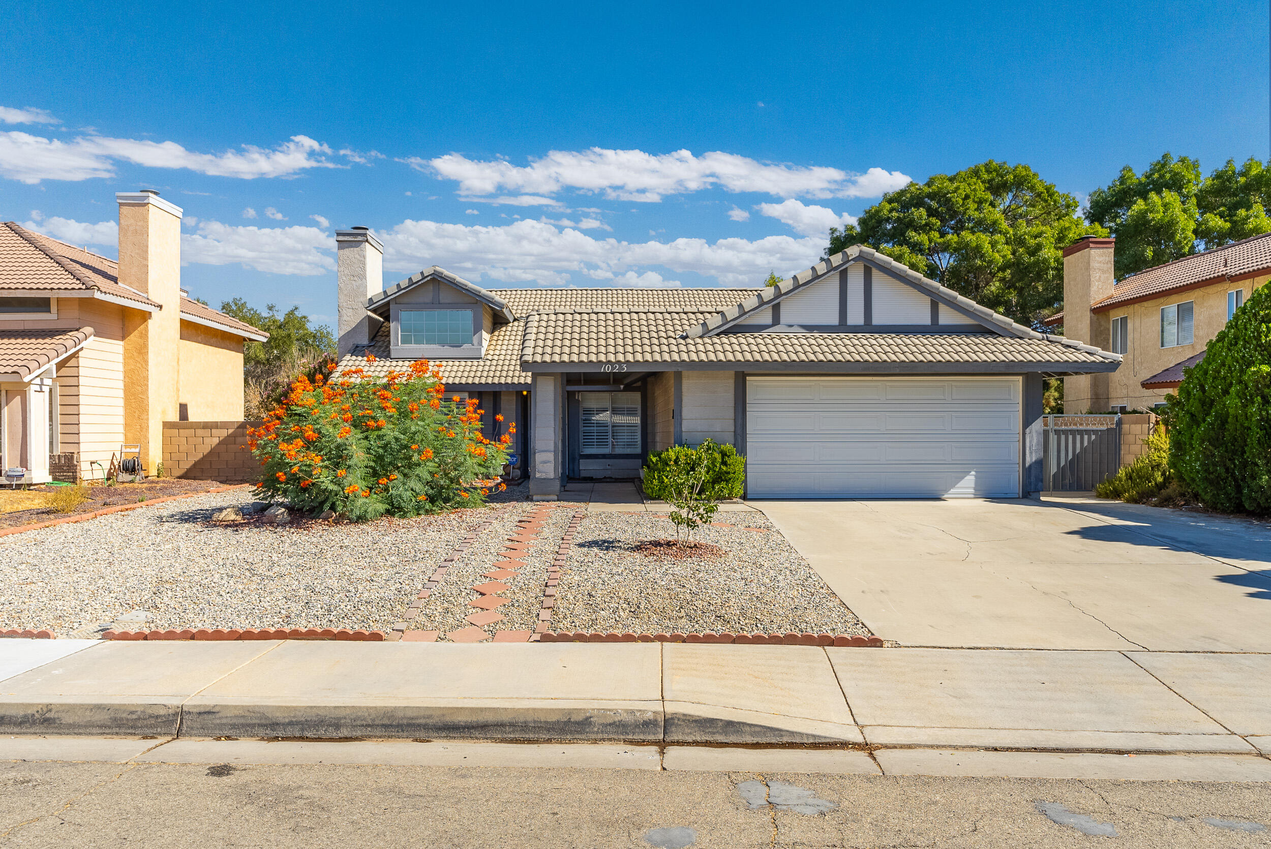 a front view of a house with garage and plants