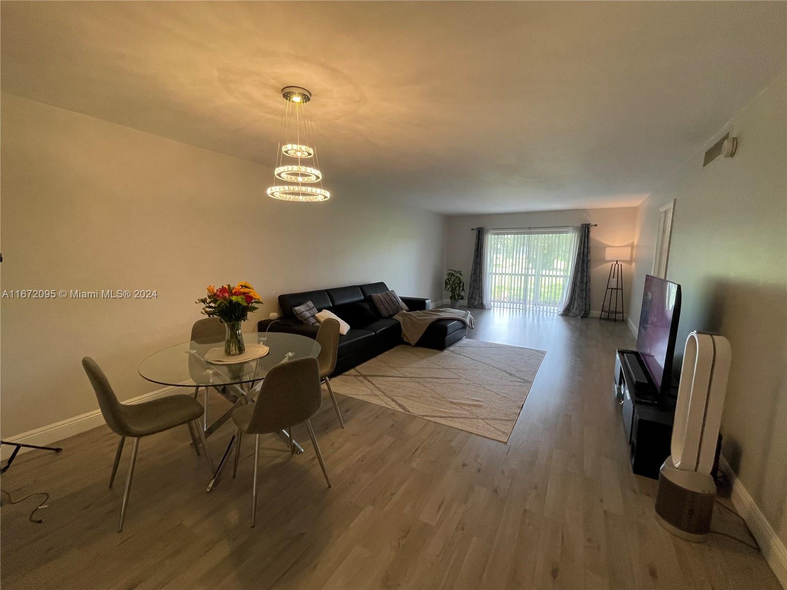 a living room with furniture a flat screen tv and a refrigerator