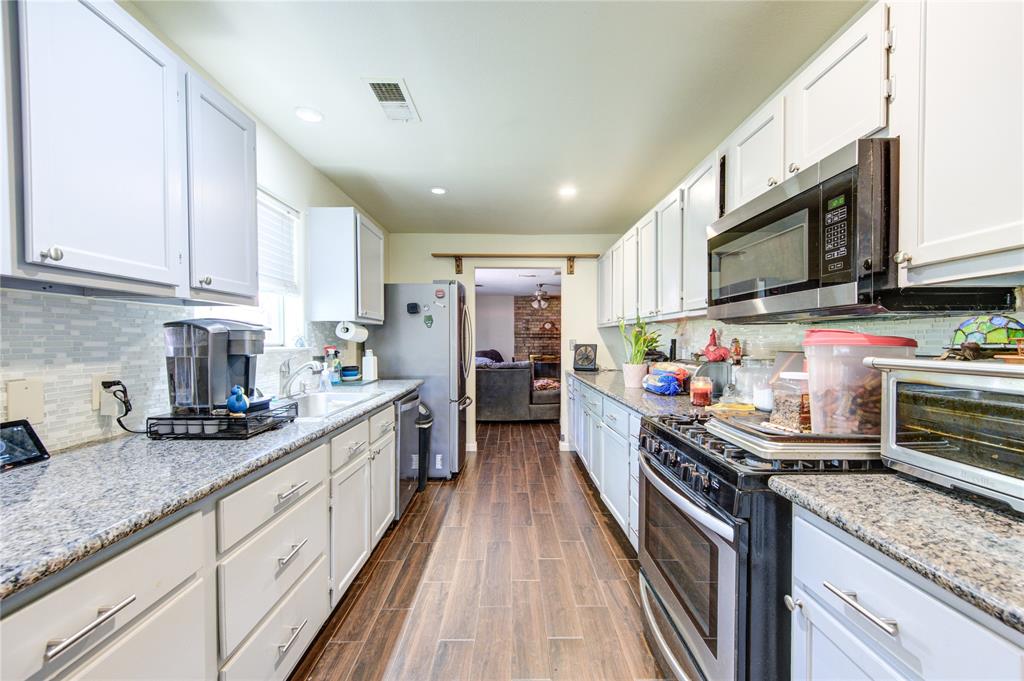 a kitchen with kitchen island granite countertop lots of counter top space and stainless steel appliances