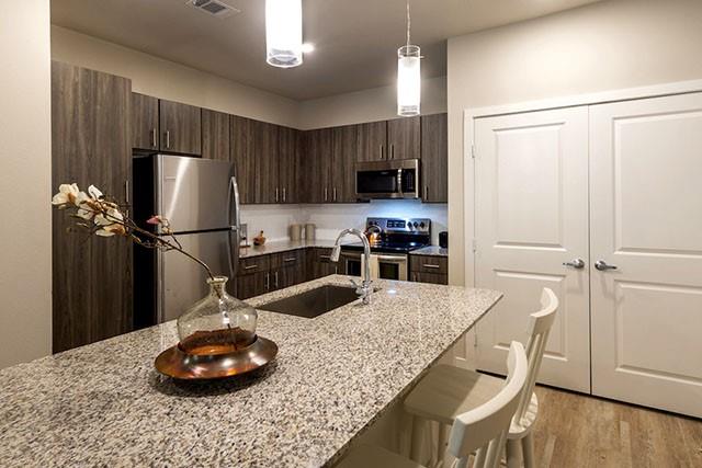 a kitchen with stainless steel appliances granite countertop a sink stove and refrigerator