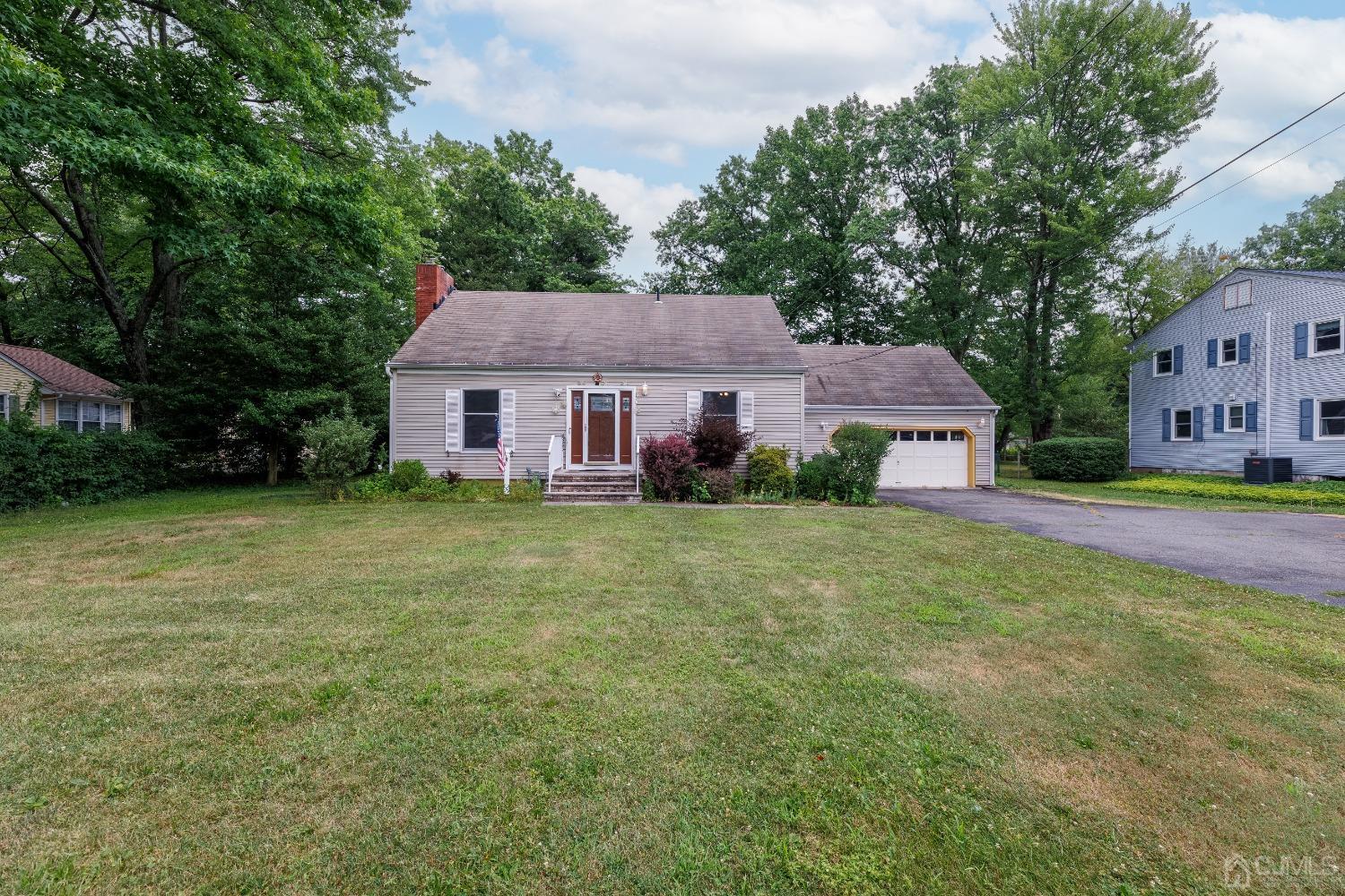 a front view of house with yard and trees in the background