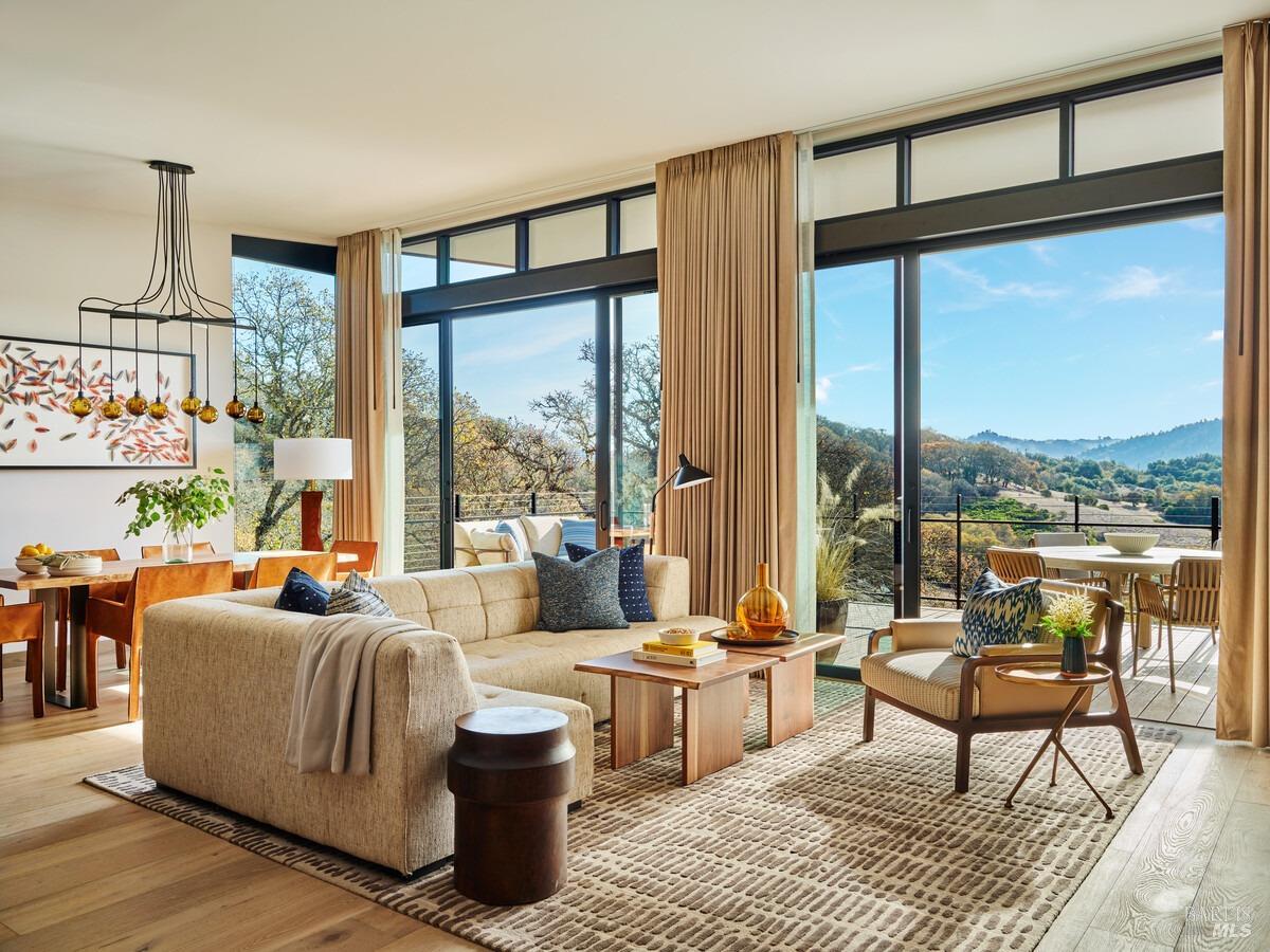 a living room with furniture large windows and wooden floor