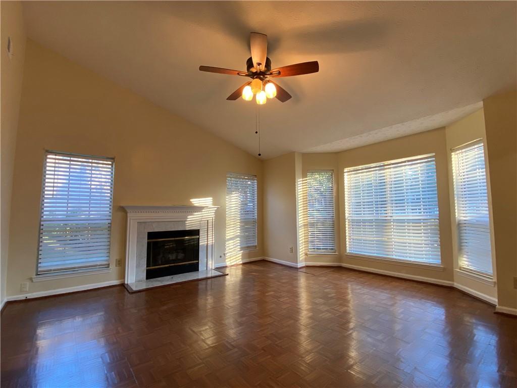 an empty room with wooden floor fireplace and windows