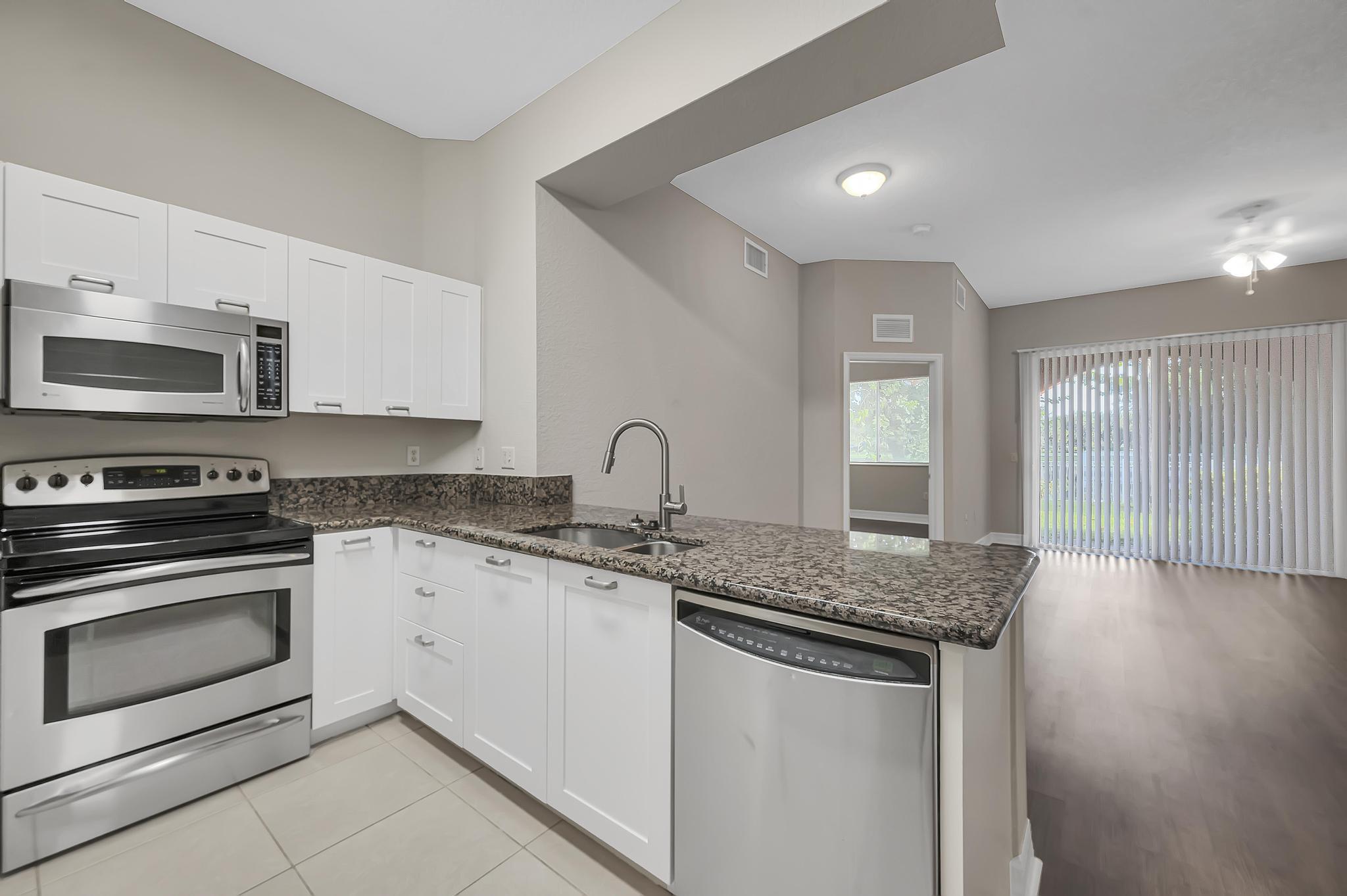 a kitchen with granite countertop a sink and a stove top oven with wooden floor