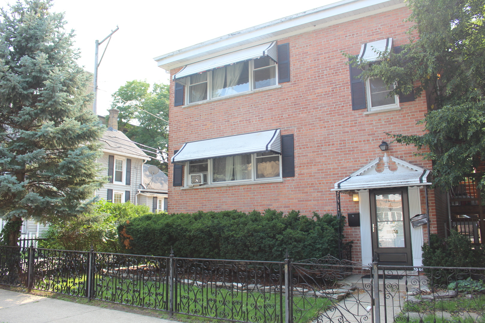 a front view of a house with glass windows and plants