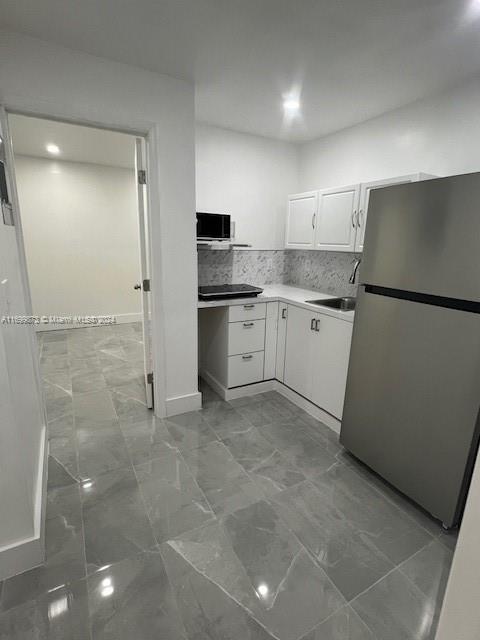 a kitchen with a sink a refrigerator and cabinets