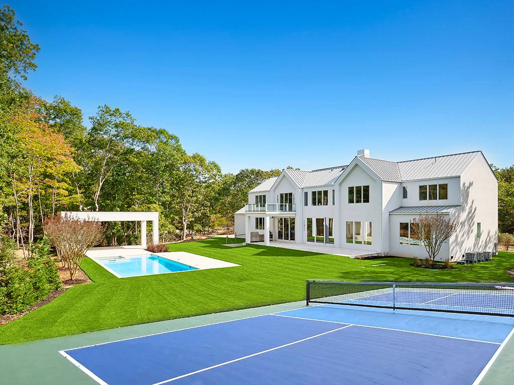 a view of a house with a big yard and large trees